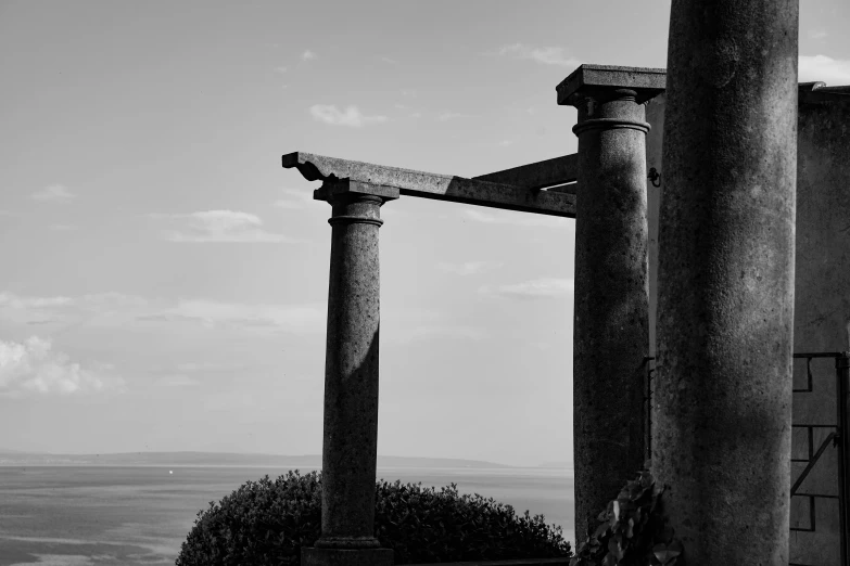 several decorative stone pillars on a hill with water in the background