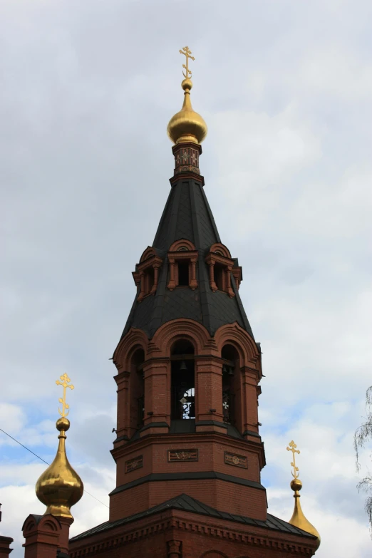 the golden bell tower is surrounded by two large domes