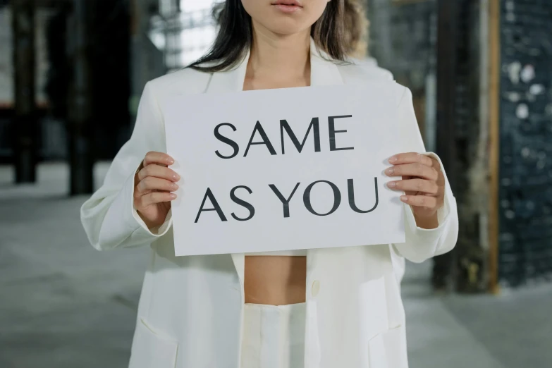 a woman holding a sign saying same as you