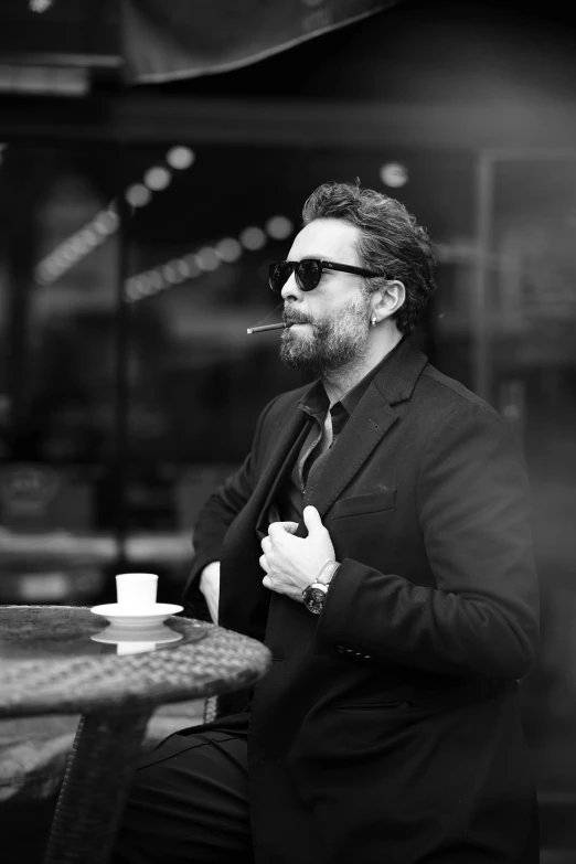 a man in sunglasses smoking a cigarette at a table