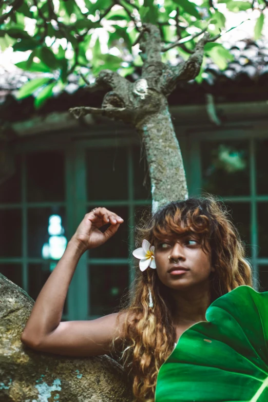 a woman standing against a tree with flowers