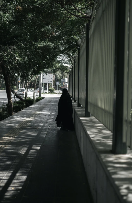 an individual standing by a wall in the shade