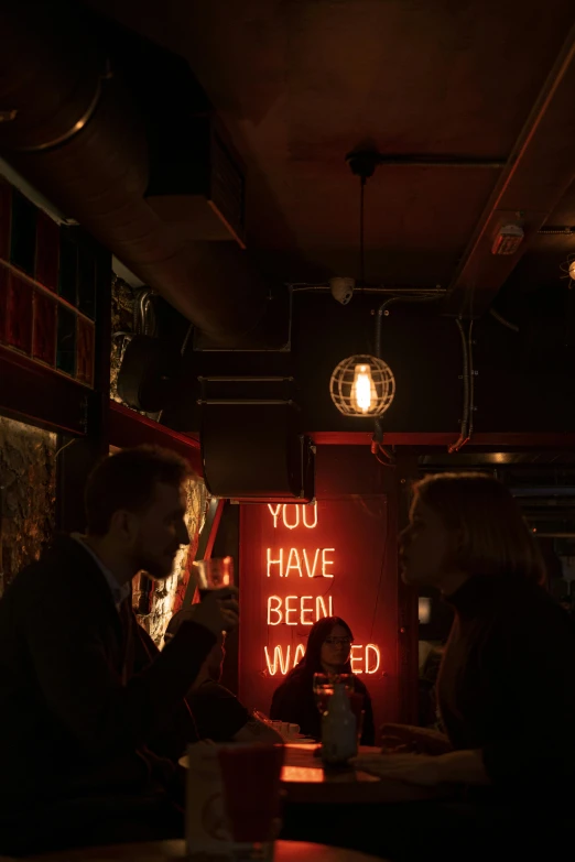 two people sitting on a bar in the dark