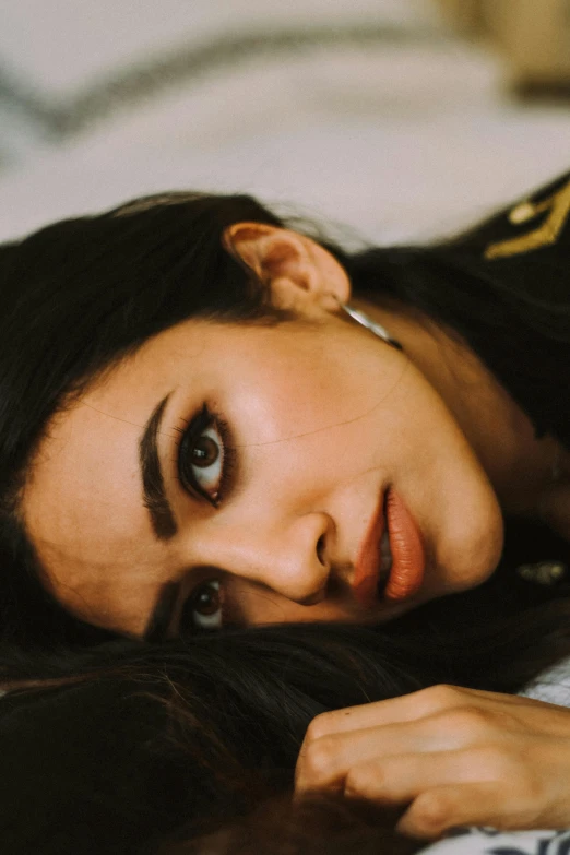 a beautiful young woman with dark hair laying on a bed