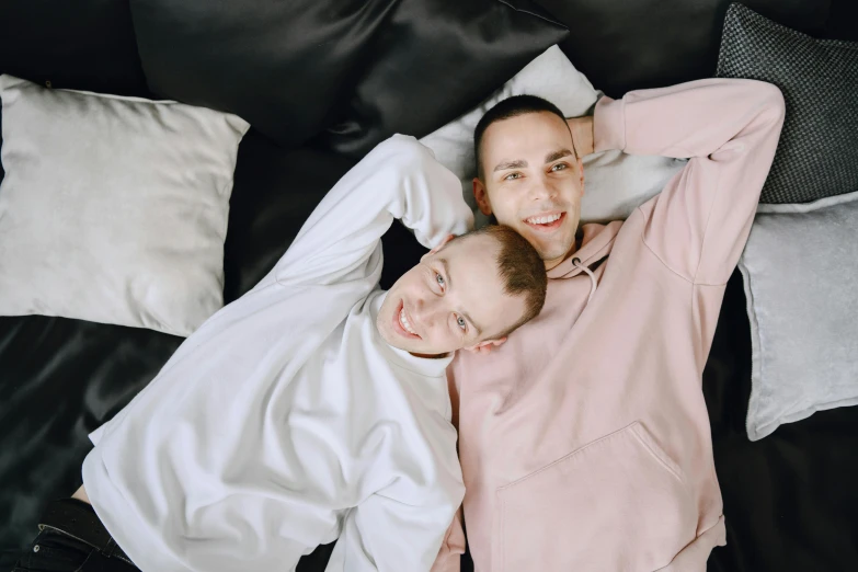 two people lying on a bed next to each other