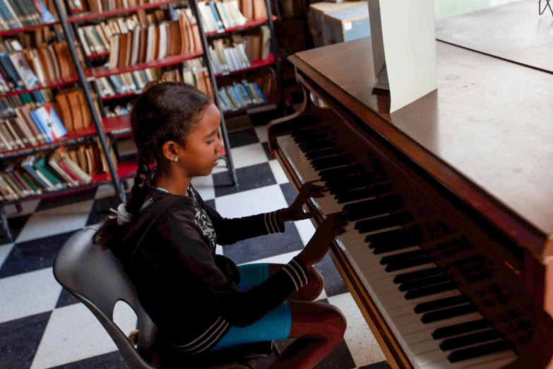 a child sits in front of a piano