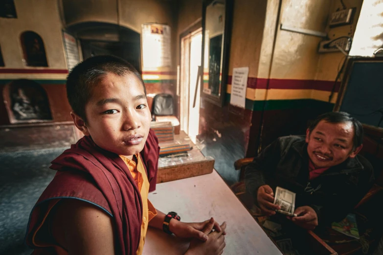 a boy sitting at a table with his teacher smiling