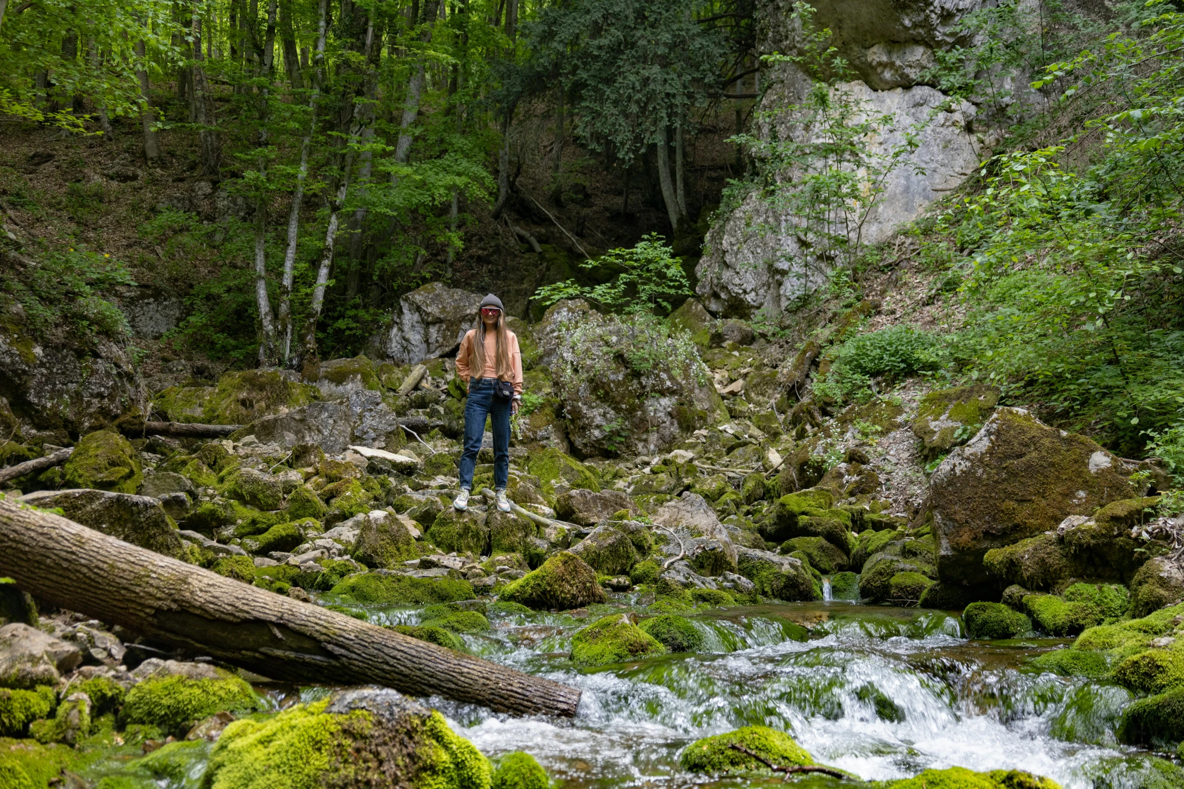 a man in a brown jacket is walking along in some green plants