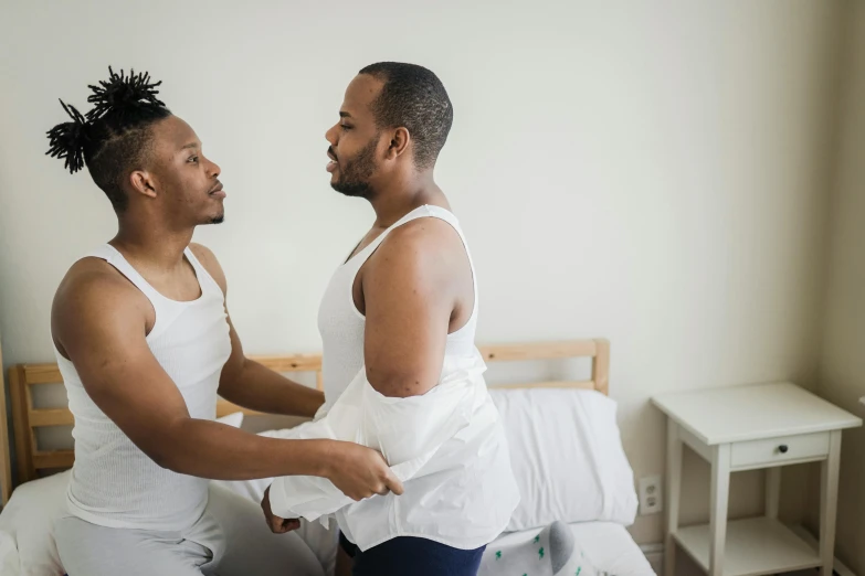 a pair of black men are talking in a bedroom