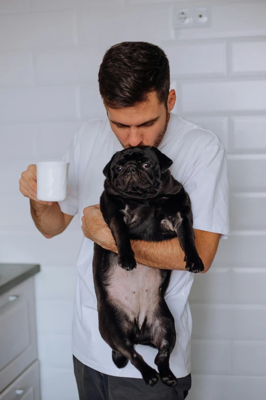 a man holding a little black dog in his arms