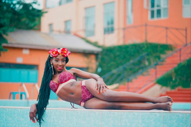 a woman sitting on a ledge next to a swimming pool