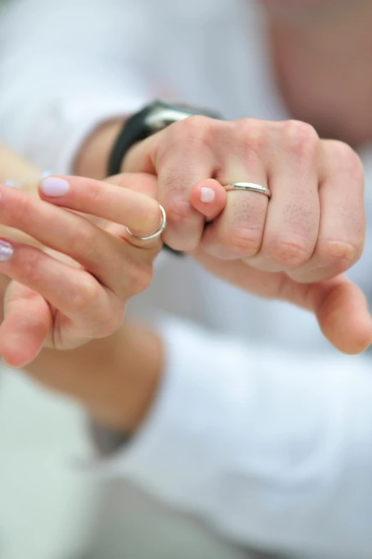 a bride and groom hold hands with wedding rings