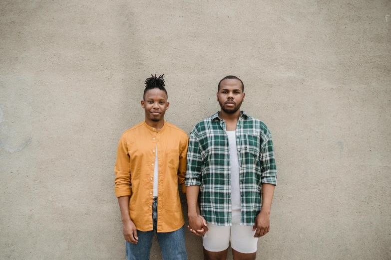 two people standing next to each other by a wall