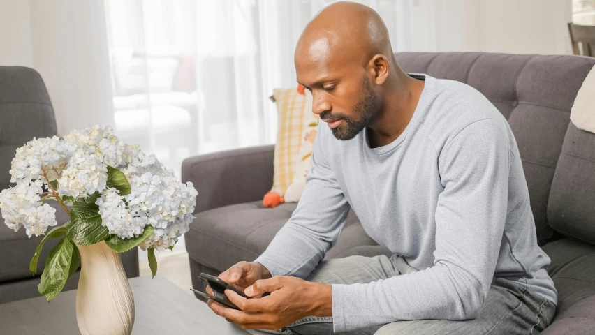 a man sitting on a couch looks at his phone