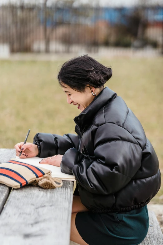 a woman sitting at a park bench writing on her journal