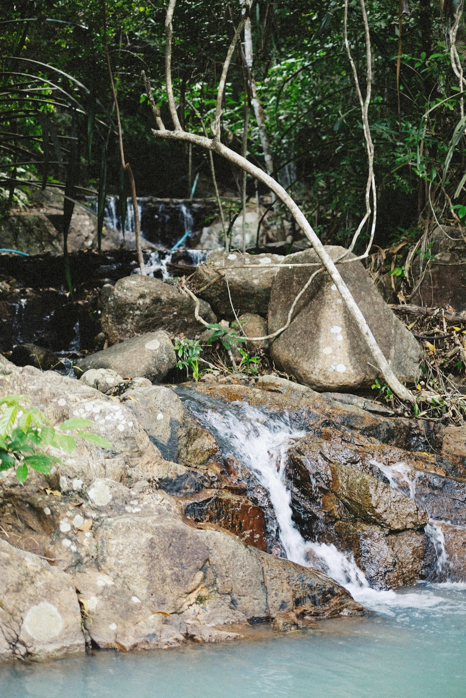 the man sits on rocks beside a river