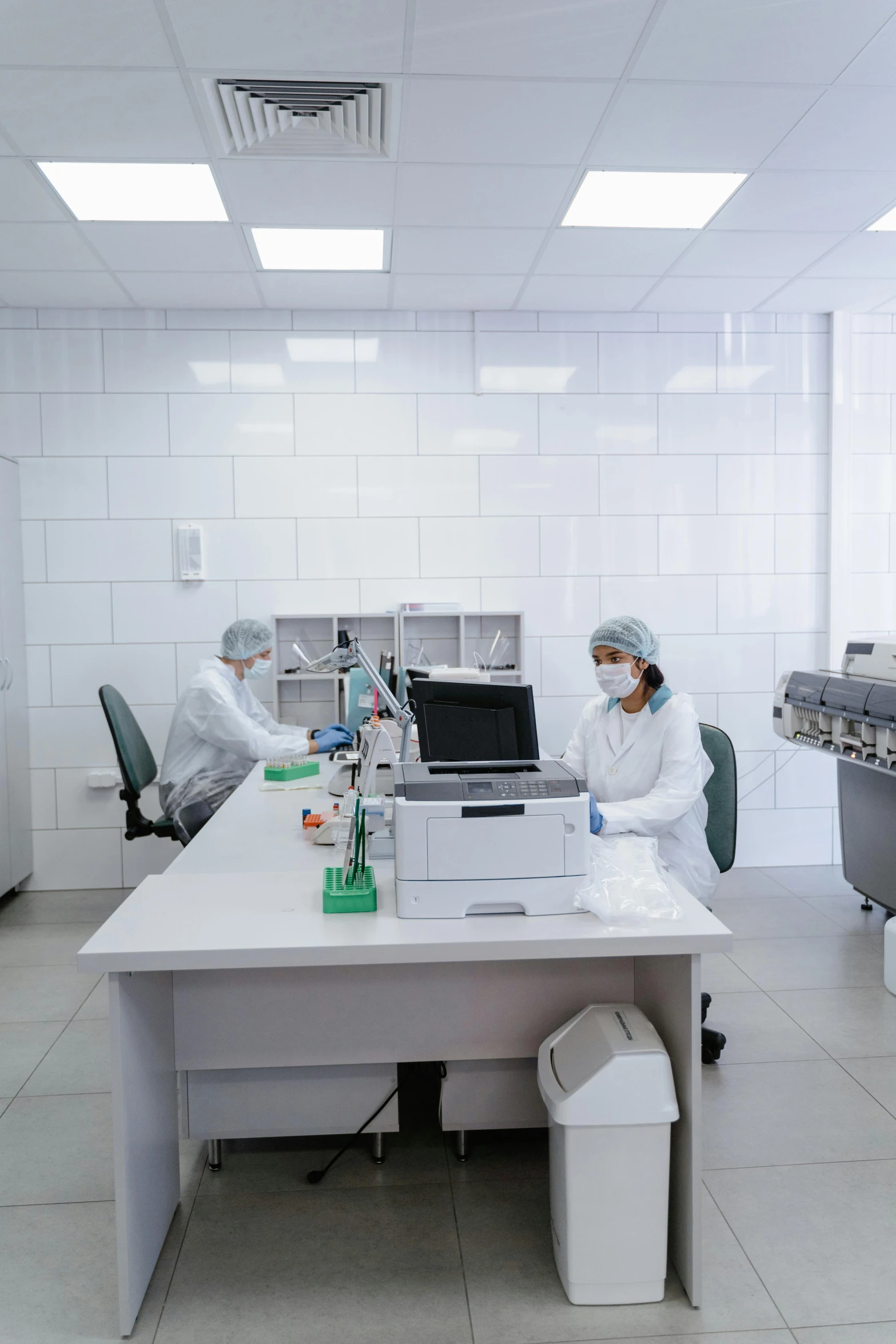 two people wearing masks are working on a lab