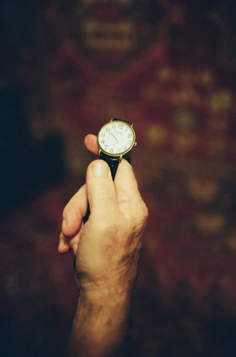 a person holds up a small pocket watch