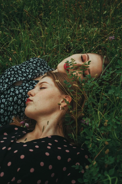 two girls laying in the grass looking at each other