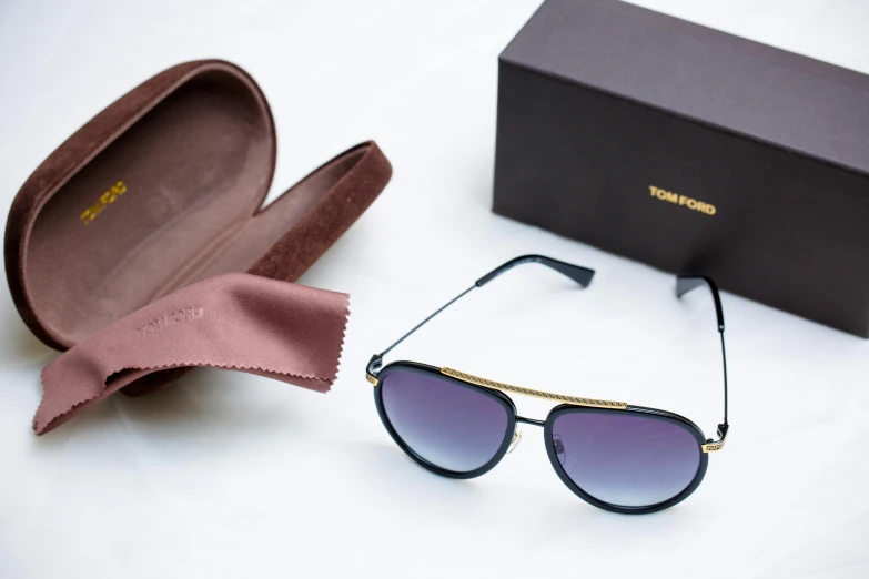 a black pair of sunglasses is laying near a box and a satin bag