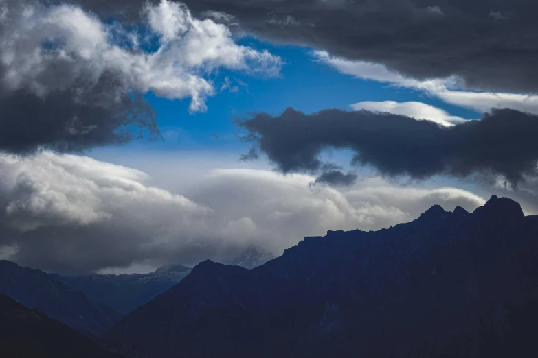 clouds float overhead on a dark mountainside