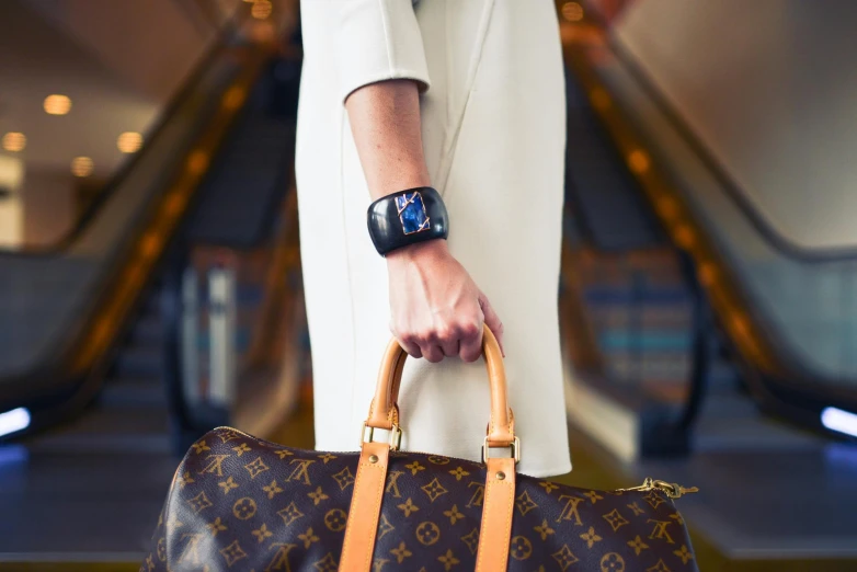 a woman's hand holds onto a purse on an escalator