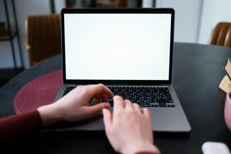 a person sits at a table typing on a laptop