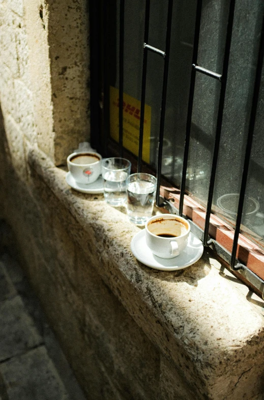 coffee cups are on a table near a window sill