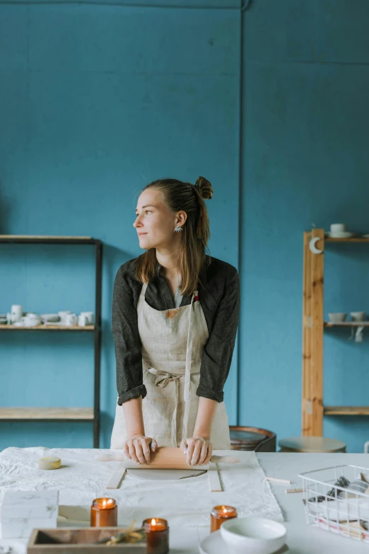 a woman with an apron on in front of a table with various types of dishes