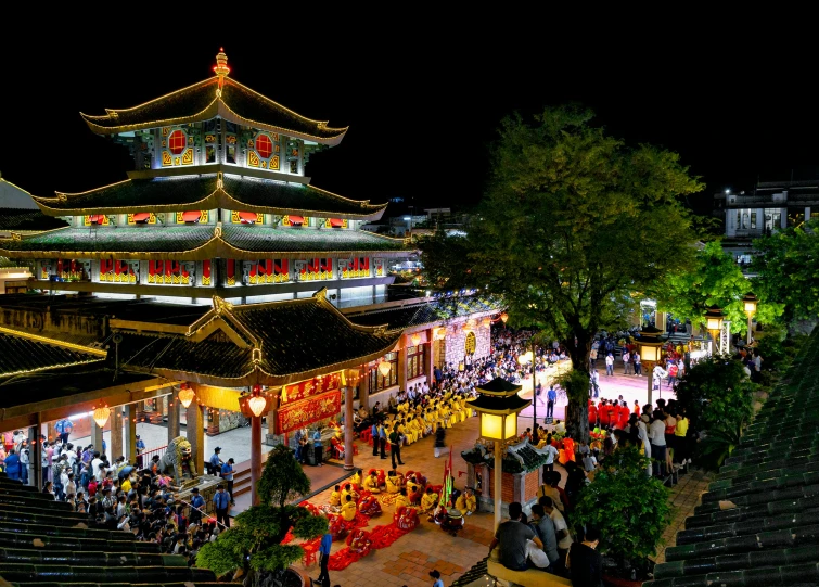 a number of people walking down a street near many lights