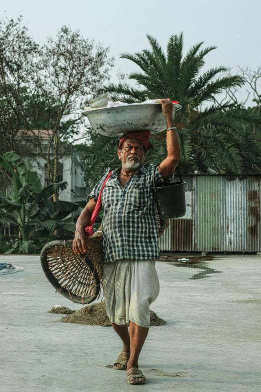 a man carrying a surfboard on his head and carrying soing in his hand