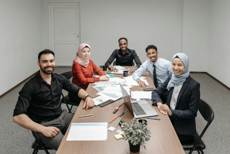 five people sitting at a long table in an office