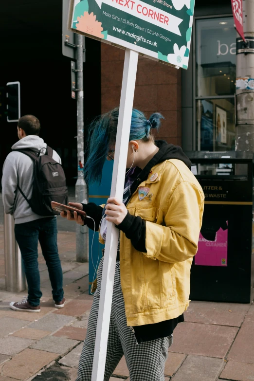 a man wearing blue hair holding a sign on the street