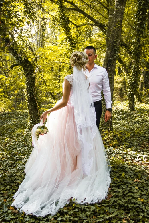 a man and a woman stand in front of trees