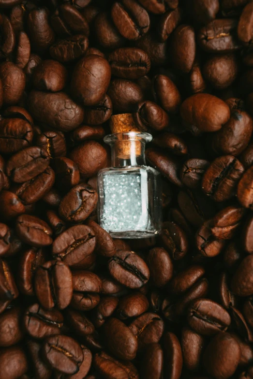 small bottle of liquid next to lots of coffee beans