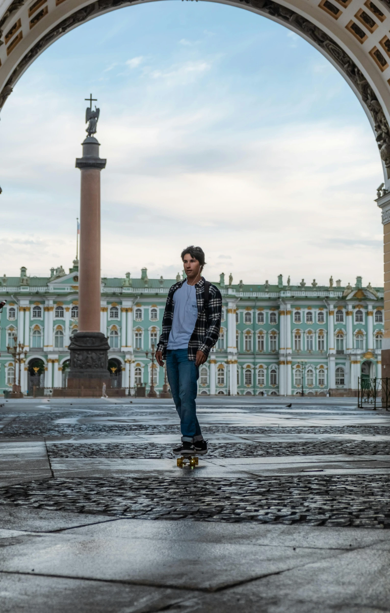 a man is standing in the middle of a courtyard with an arch and statue