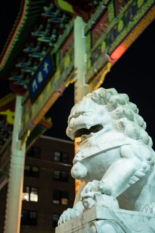 a statue of a seated lion with a building in the background