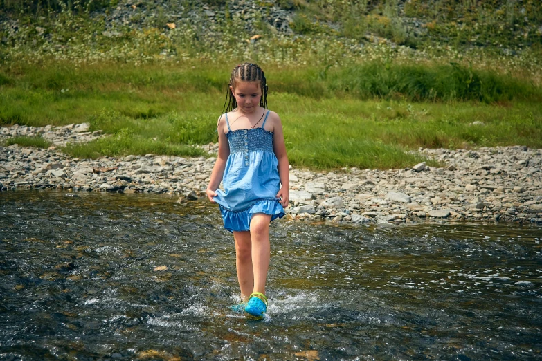 the girl is wearing a blue dress by the water