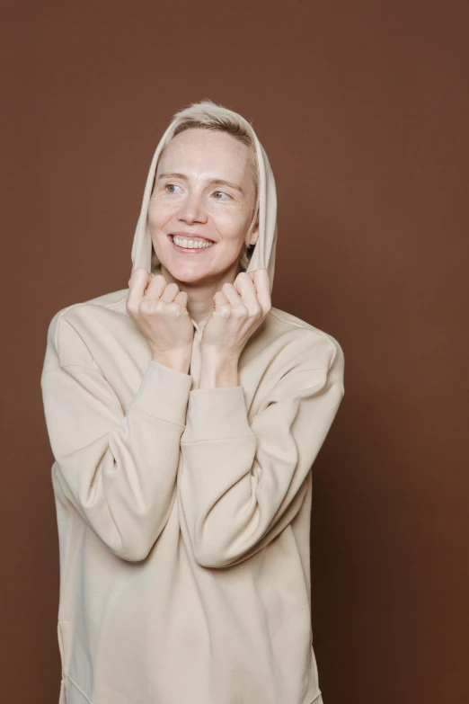 a woman with blonde hair standing with her hands behind her head