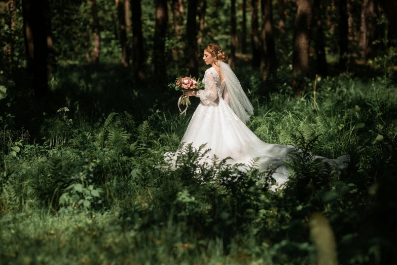 a bride in a wedding dress is walking through a grove of grass