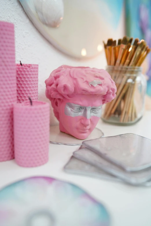 a pink sculpture, some candles and some pink brushes