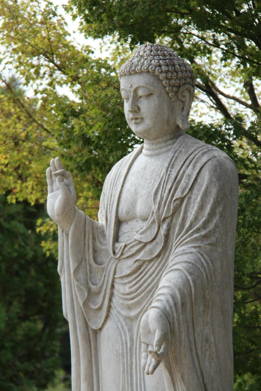 a marble statue in a garden sits and holds soing up