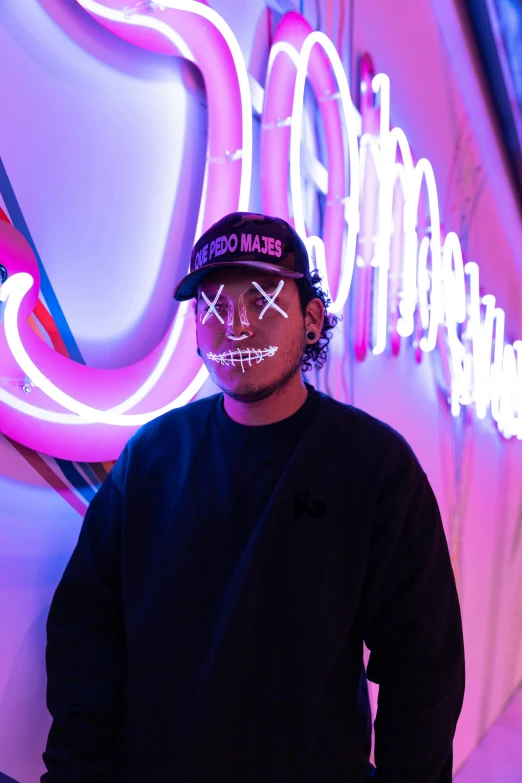 man with painted face standing in front of neon lights