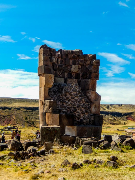 a very tall rock structure in a grassy field