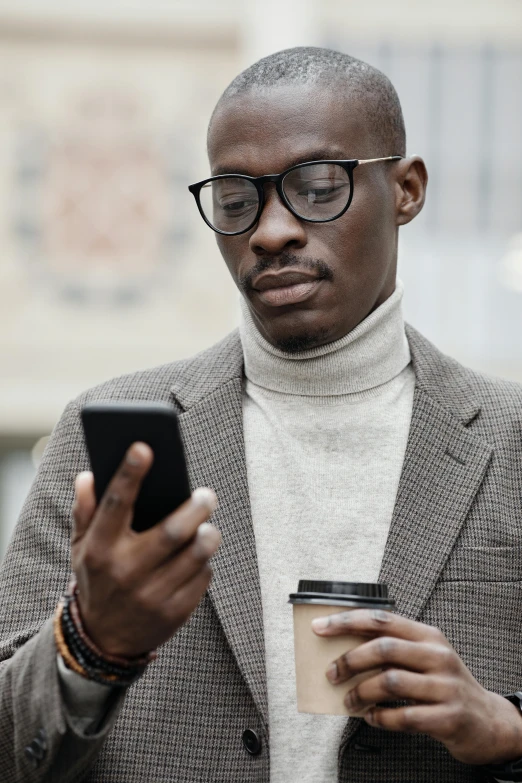 a man in glasses is looking at a cell phone