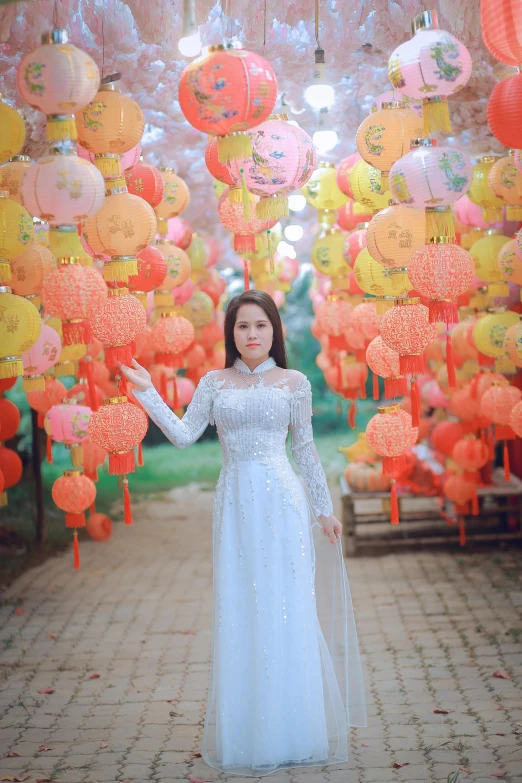 woman in white dress standing under over a canopy of paper lanterns