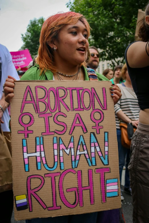 a person with an expression holding a sign at a protest