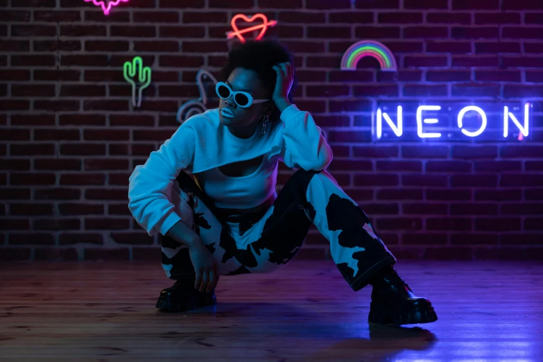 a young woman with dark sunglasses is posing in front of a neon sign