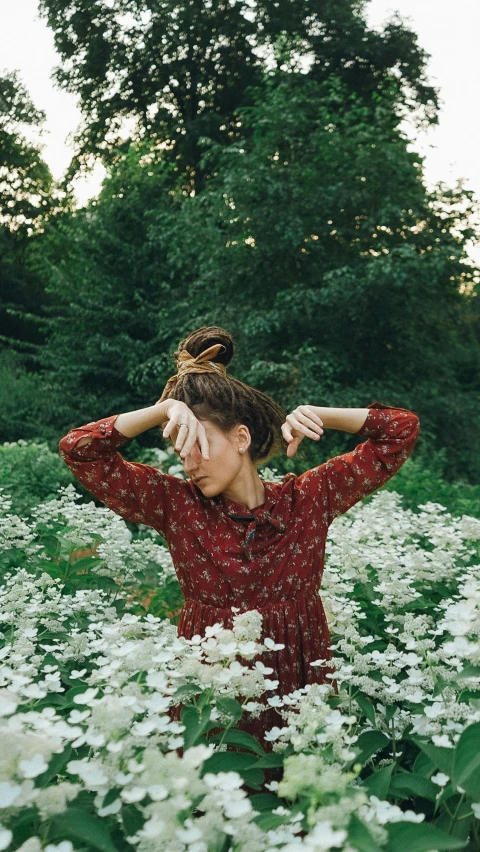 young woman holding her hands over her eyes while in the middle of a field