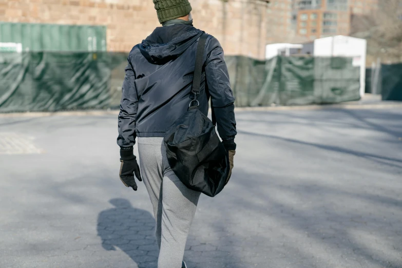 a person wearing a jacket and hat walking down the street